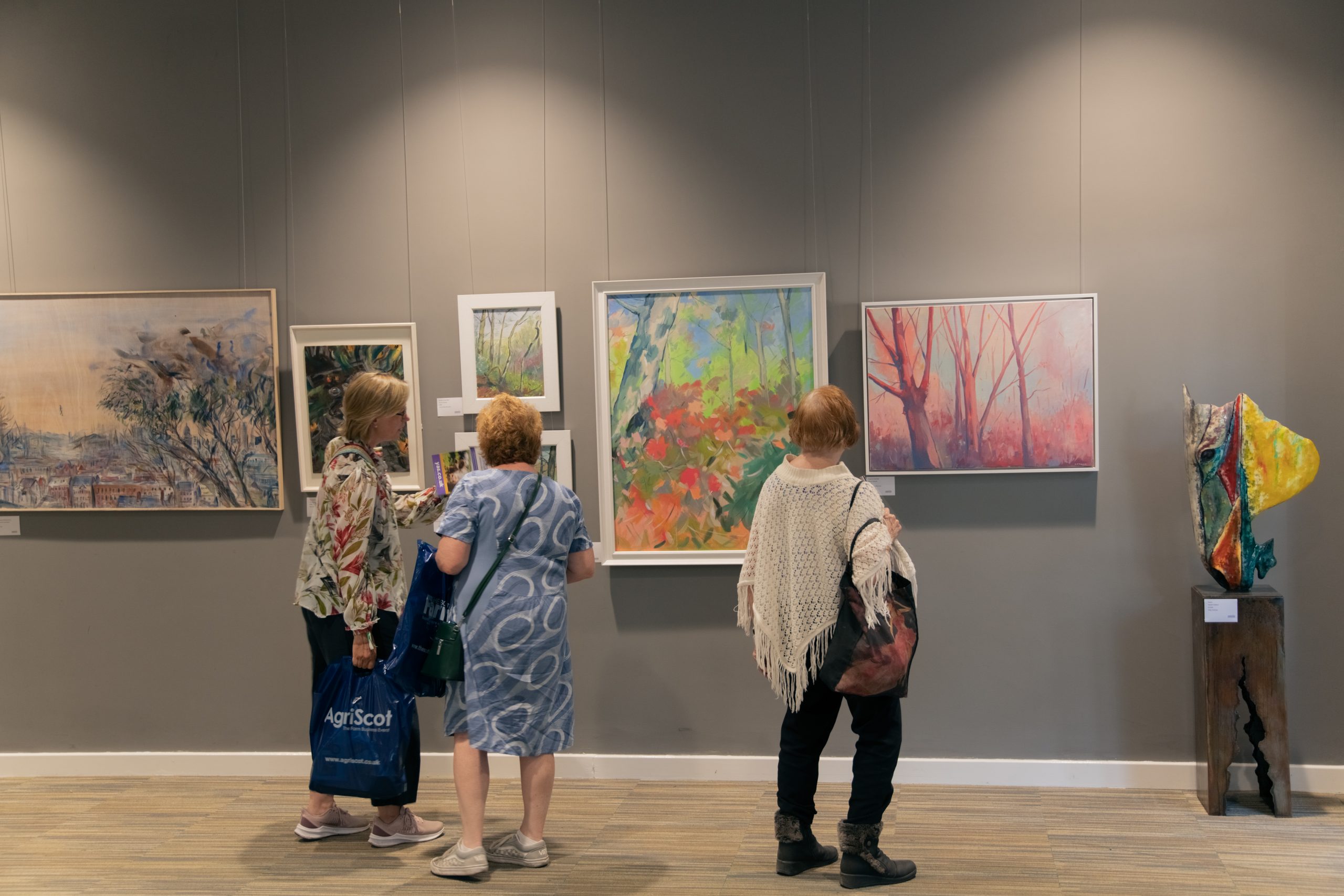 Vistors looking at paintings hanging on a great wall at the Great Yorkshire Show Art Show